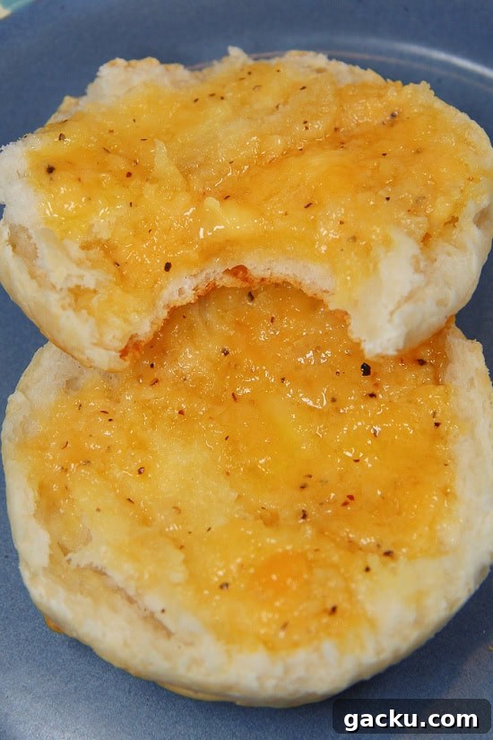 Two hot dinner rolls with melted butter and finely grated cheddar on top.