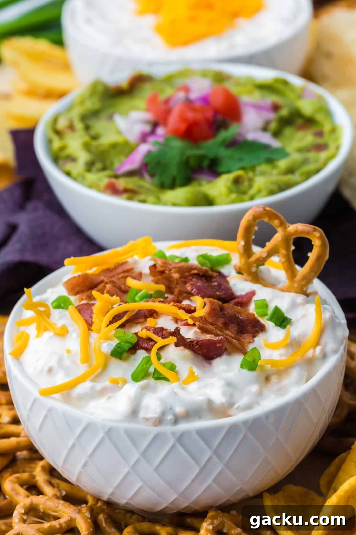 Creamy Loaded Baked Potato Dip Recipe for Parties and Game Day 2 A bowl of baked potato dip with a pretzel dipped on the side.