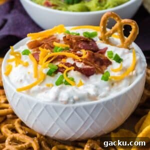 Creamy Loaded Baked Potato Dip Recipe for Parties and Game Day 9 A bowl of loaded baked potato dip topped with shredded cheese, bacon, and green onion.