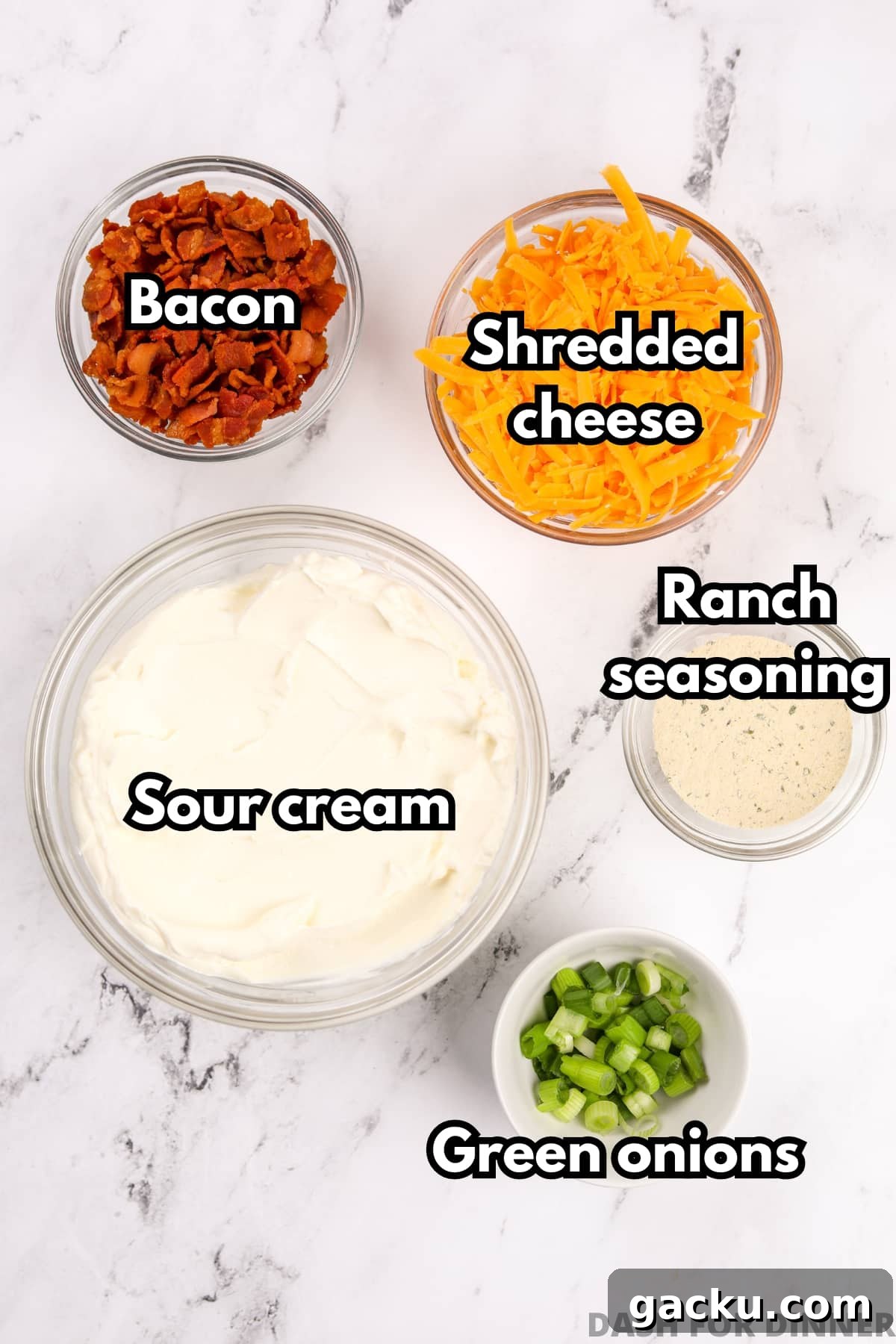 Creamy Loaded Baked Potato Dip Recipe for Parties and Game Day 3 An overhead view of bowls of ingredients, including sour cream, shredded cheese, bacon, ranch seasoning, and green onions.