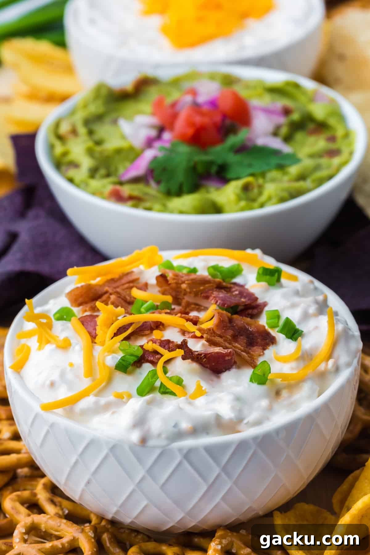 Creamy Loaded Baked Potato Dip Recipe for Parties and Game Day 7 A small white bowl filled with baked potato dip, topped with cheddar cheese, bacon, and green onion.