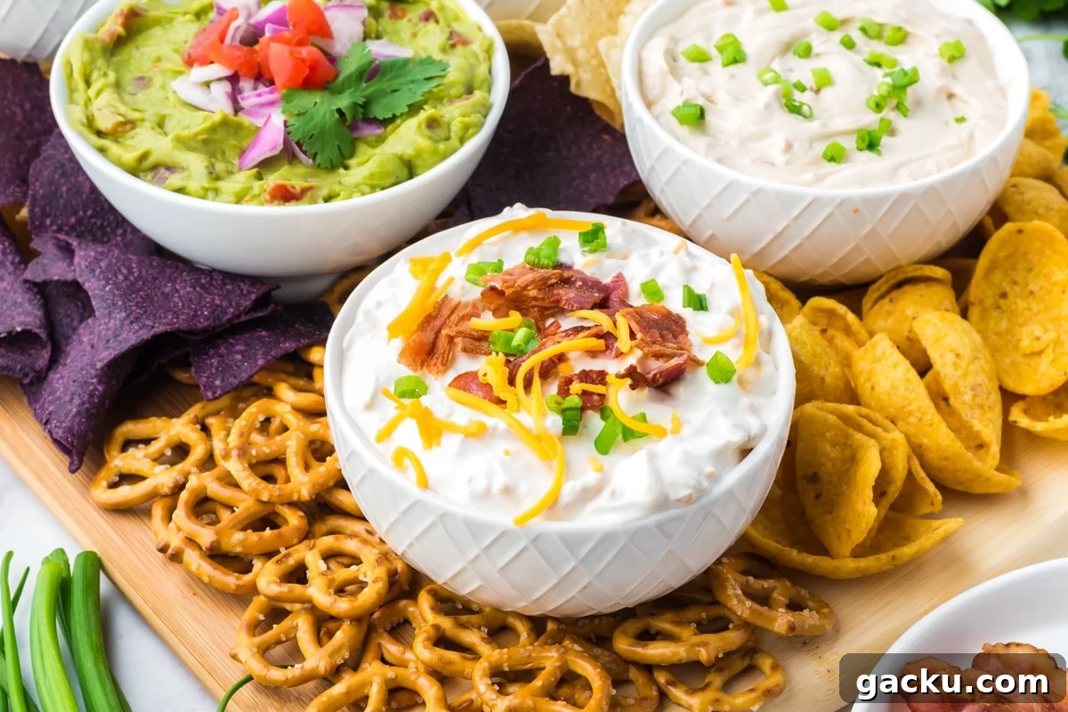 Creamy Loaded Baked Potato Dip Recipe for Parties and Game Day 8 Three bowls of various dips, surrounded with blue corn tortilla chips, corn chips, and pretzels.