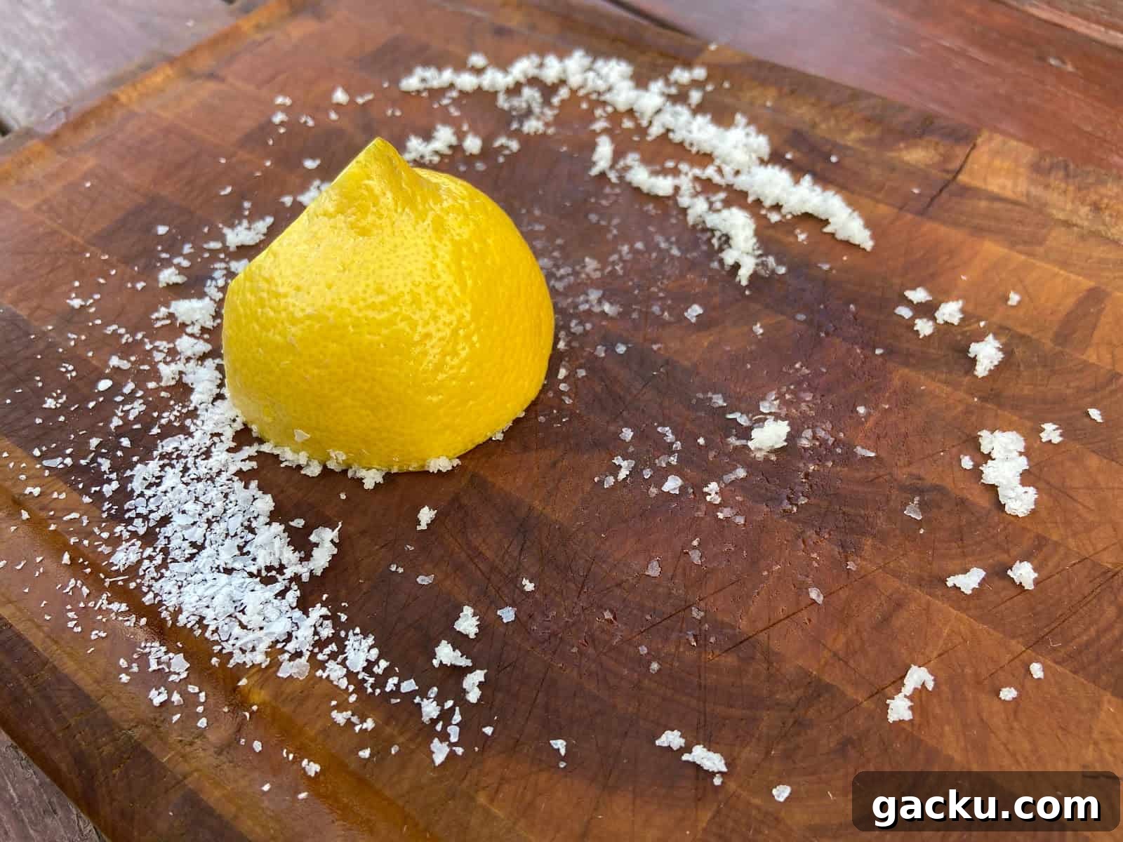 Cutting board with sliced lemon and salt on top.