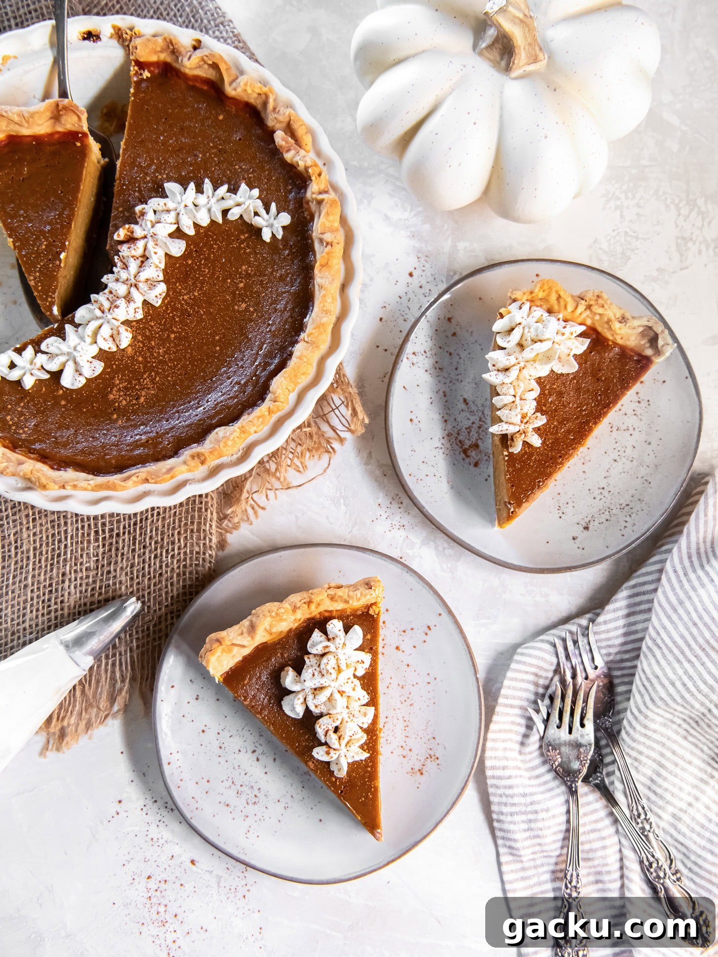 Homemade Pumpkin Pie Recipe: Classic Scratch-Baked Pie 2 pumpkin pie slices on round plates with forks next to pie plate with remaining pie.