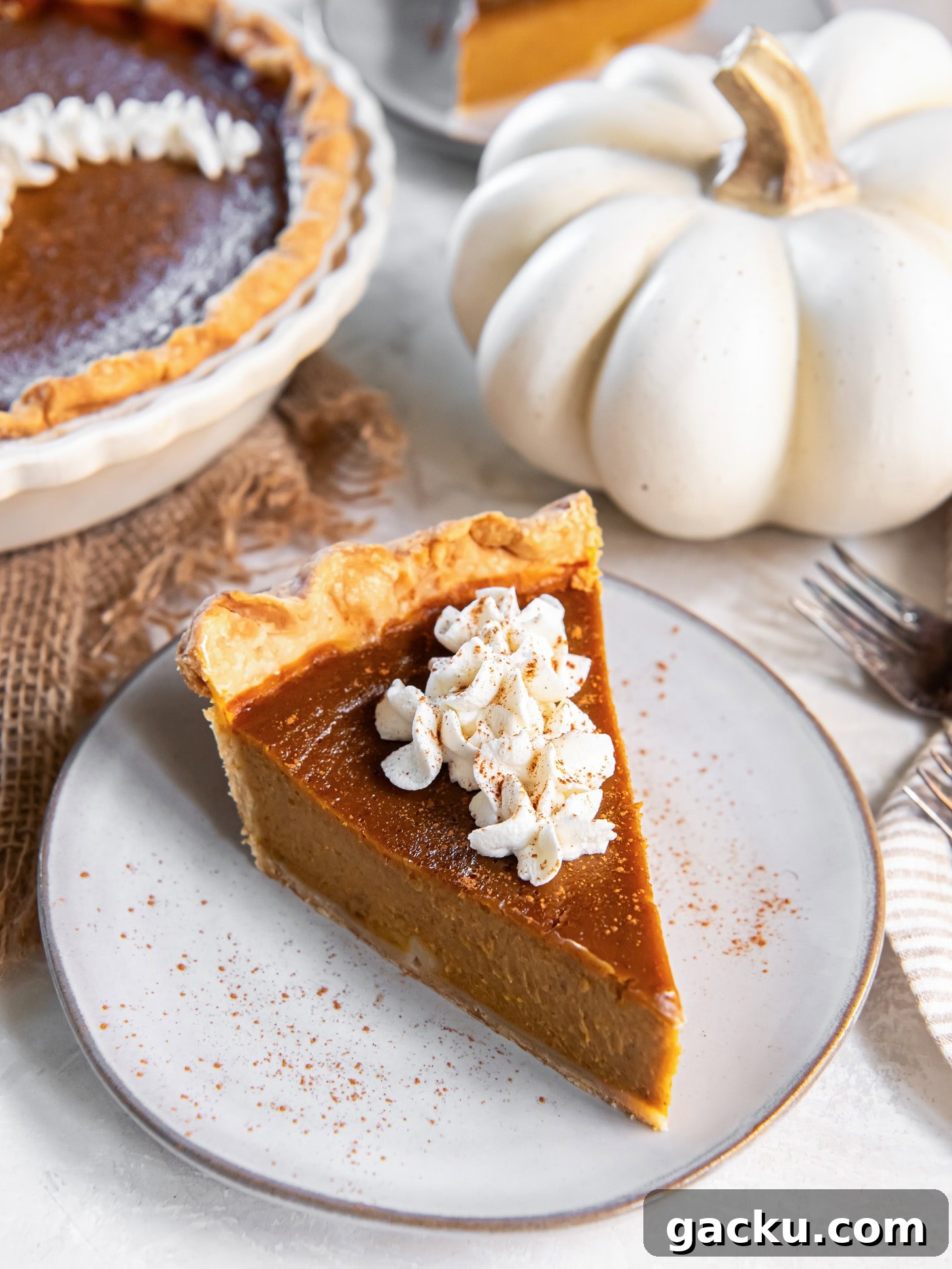 Homemade Pumpkin Pie Recipe: Classic Scratch-Baked Pie 7 slice of pumpkin pie on plate with fork taking a bite.