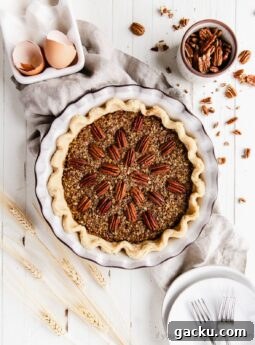 pecan pie in a ceramic pie dish with pecan halves on top arranged to radiate out