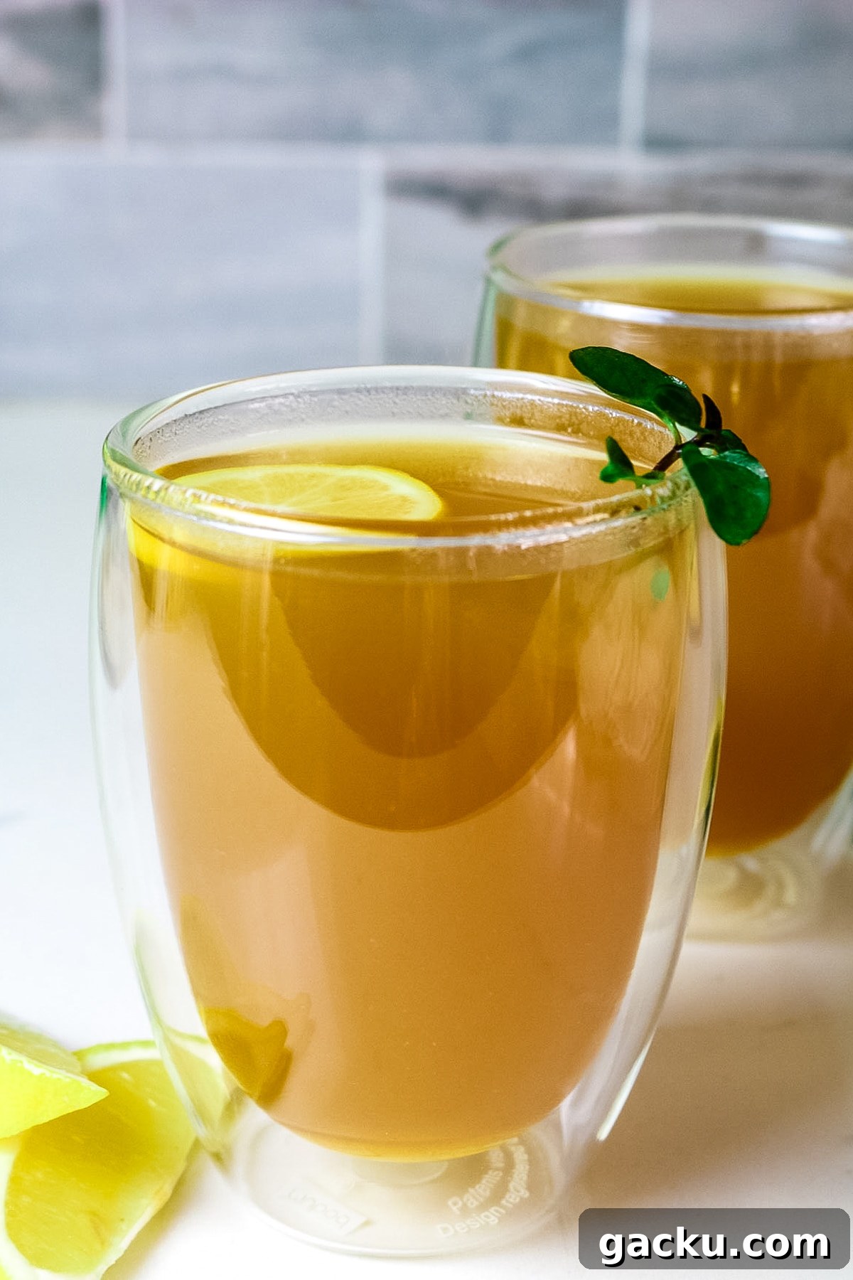 clear cups with honey citrus mint tea and lemon slices and edges and fresh mint as garnish.
