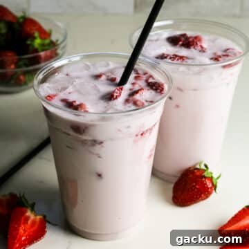 starbucks pink drink in plastic cups with fresh strawberries on the side.