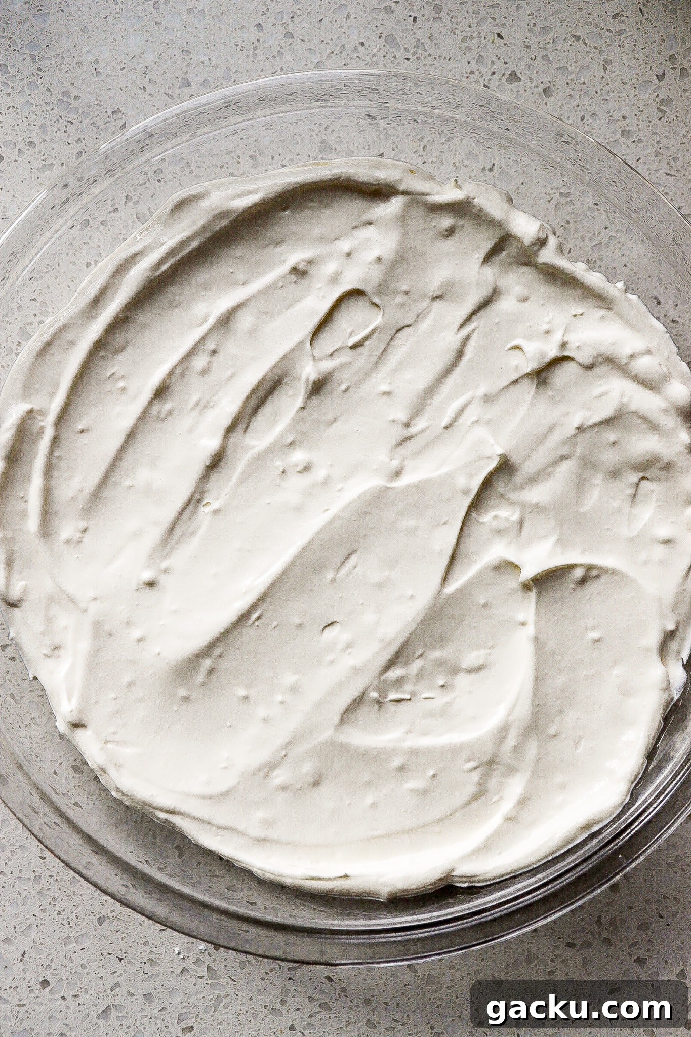 Top down view of cream cheese mixture at the bottom of a round glass dish.