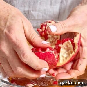 Woman peeling open fresh pomegranate.