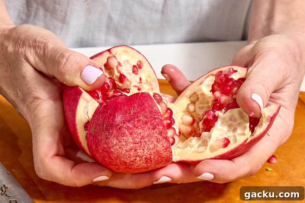Woman prying open a sliced pomegranate.
