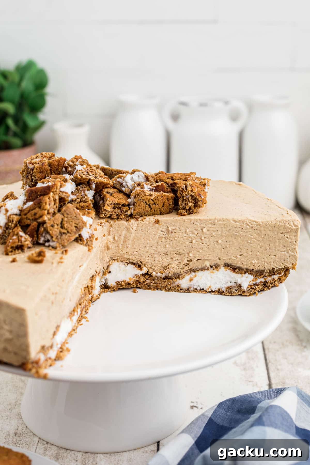 A cake stand with an oatmeal creme pie cheesecake with slices removed.