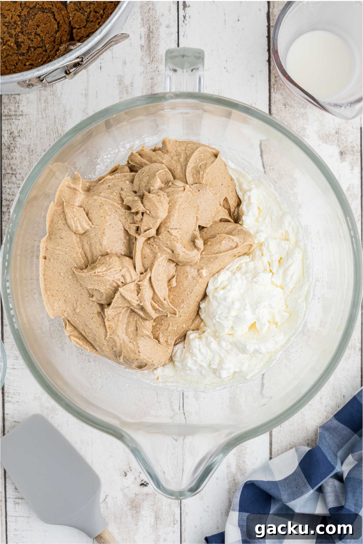 Cream cheese folding into whipped cream in a large mixing bowl.