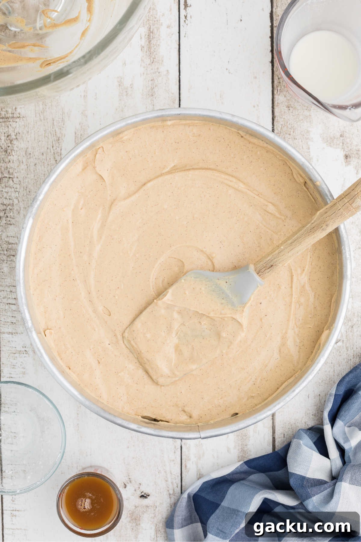 A cheesecake being smoothed out with the back of a spatula.