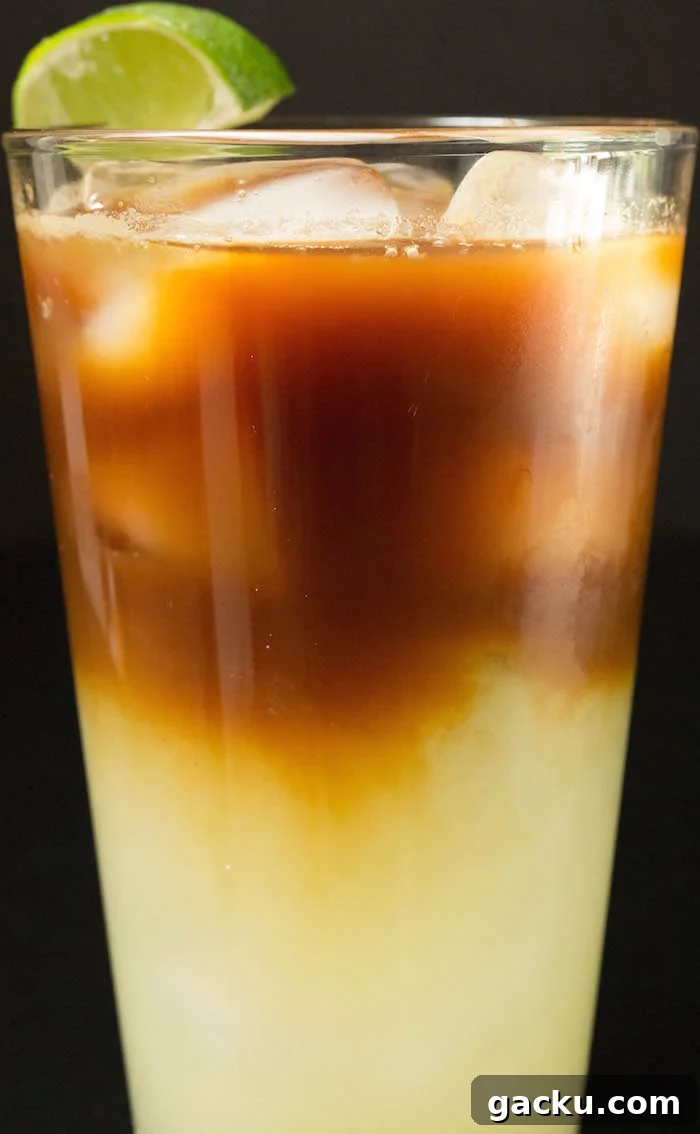 Medium close up of a layered Caipirinha cocktail with espresso on top.