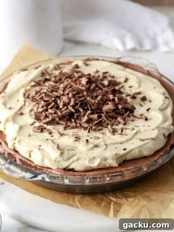 Chocolate pie with peanut butter whipped cream and chocolate shavings in a glass pie plate.