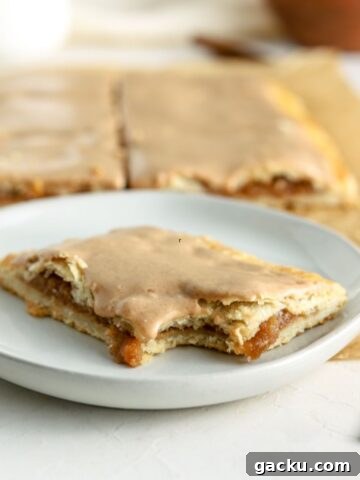 An apple pop tart with a bite taken out of it on a small plate.