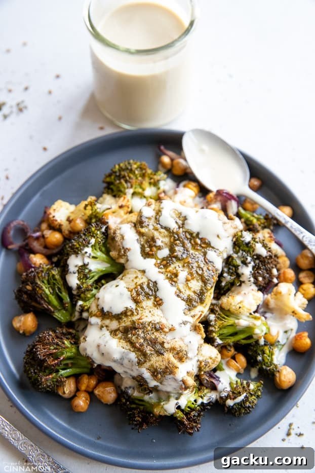 sheet pan chicken dinner overhead shot of a serving of za'atar spiced sheet pan chicken dinner with roasted vegetables, chickpeas and drizzled with tahini sauce