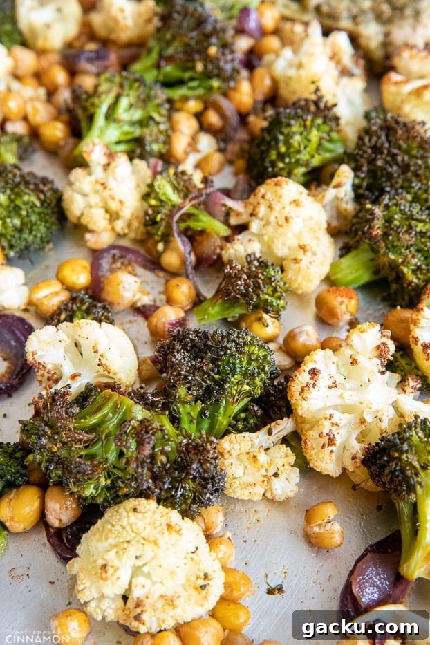 sheet pan chicken dinner broccoli, cauliflower and chickpeas roasted until crispy and charred on a baking sheet