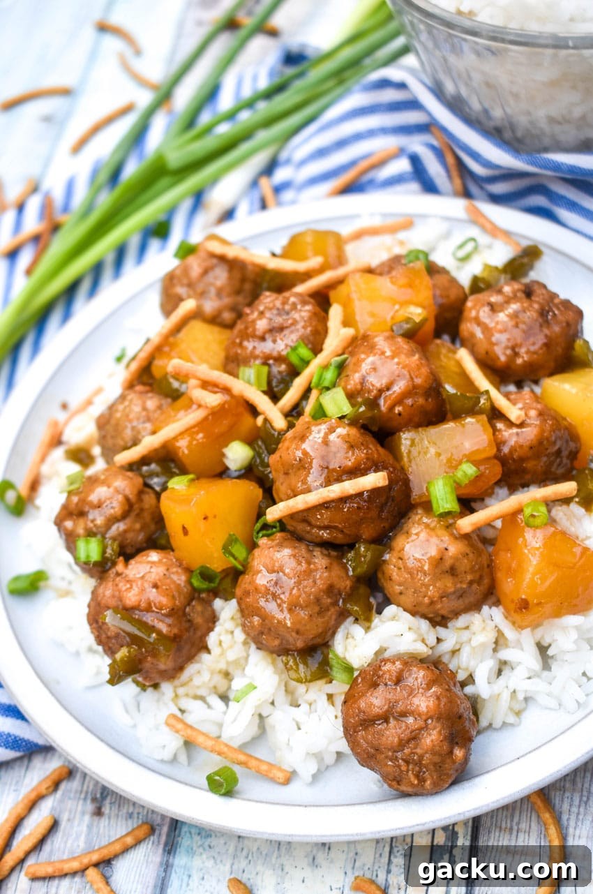 crockpot hawaiian meatballs over steamed white rice on a white dinner plate