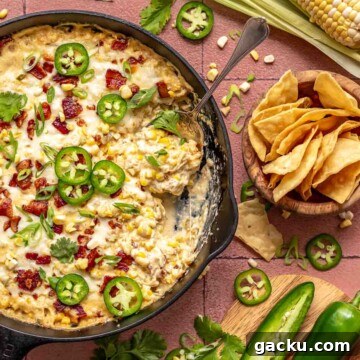 Jalapeno corn dip in a skillet with a spoon and chips on the side.