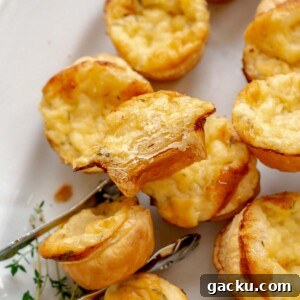 Mini Cheese Tartlets Recipe: Crispy Crusts with Creamy Filling 17 Tongs hold a cheese tartlet on a platter with a bite removed.