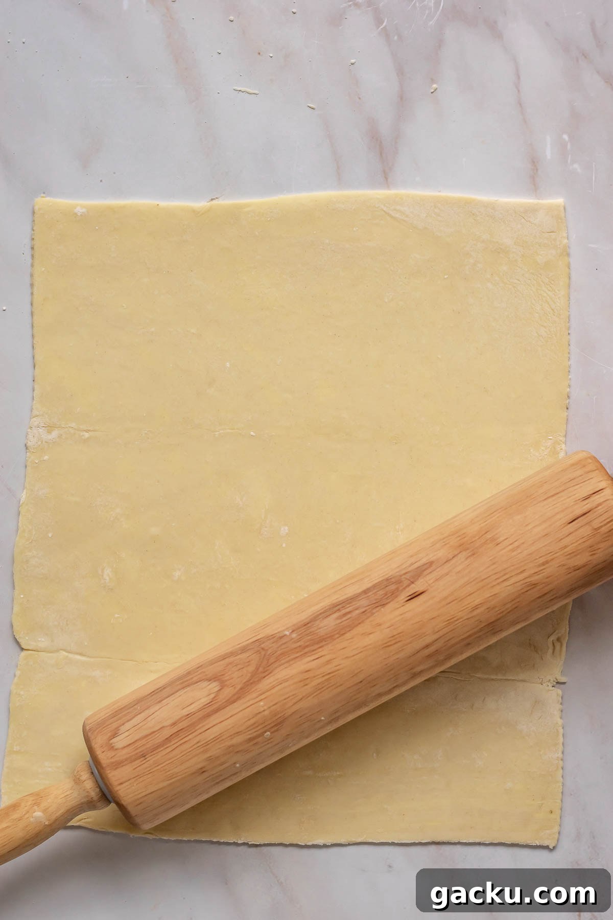 Mini Cheese Tartlets Recipe: Crispy Crusts with Creamy Filling 6 A rolling pins rolls out puff pastry.