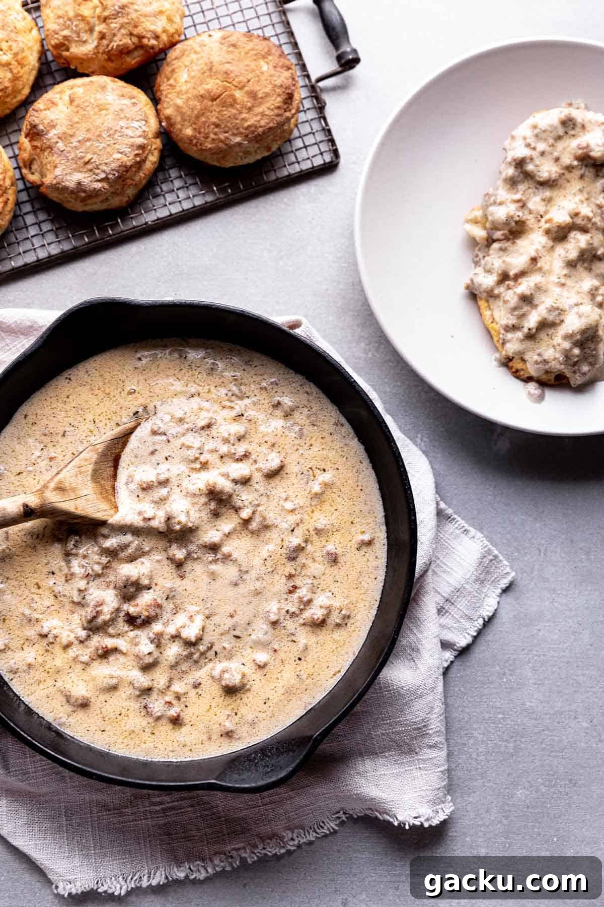 Southern-Style Sausage Gravy Recipe for Biscuits and Breakfast 5 A pan with sausage gravy, a cooling rack with biscuits and a plate of biscuits and gravy.