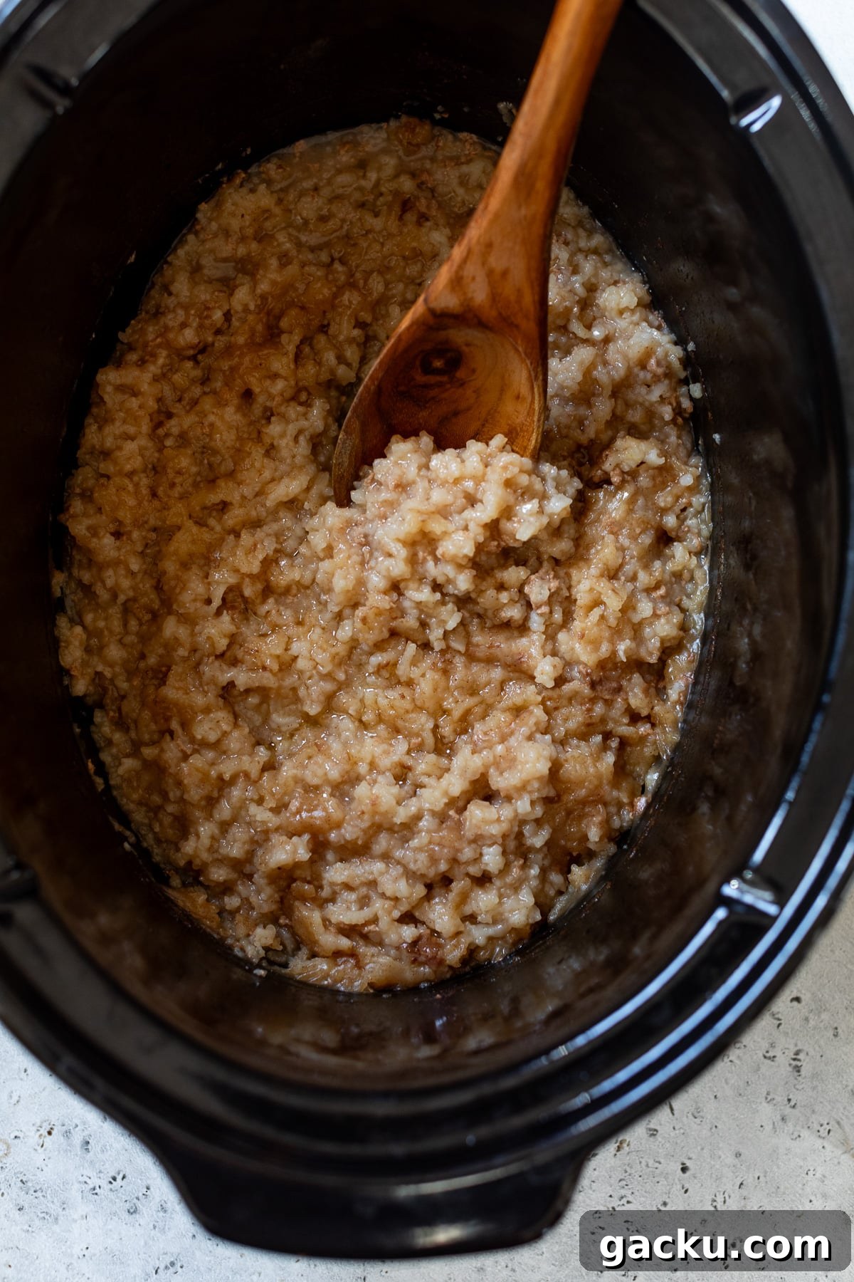 rice pudding in a slow cooker with a wooden spoon