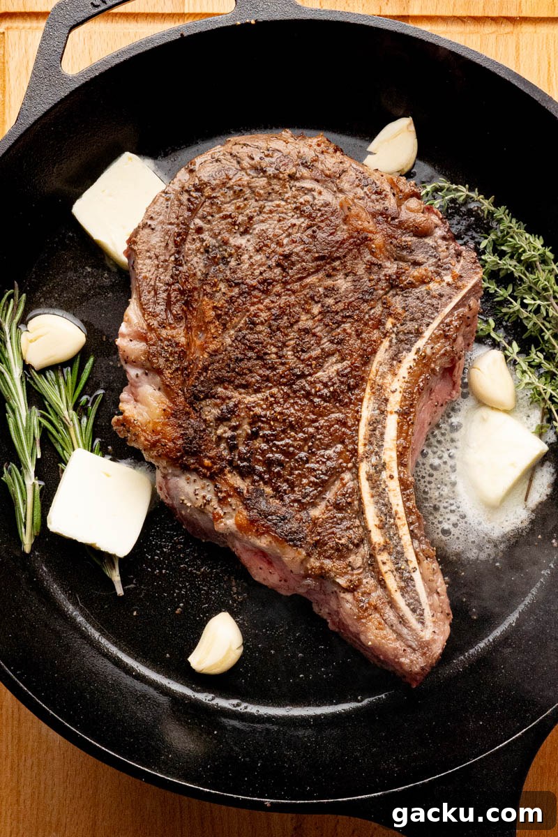The butter, garlic, rosemary and thyme in the pan with the seared ribeye steak.