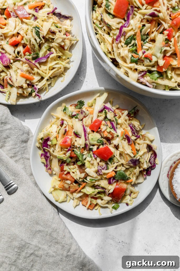 two white salad plates of southwestern style coleslaw next to a big white bowl of the slaw salad.