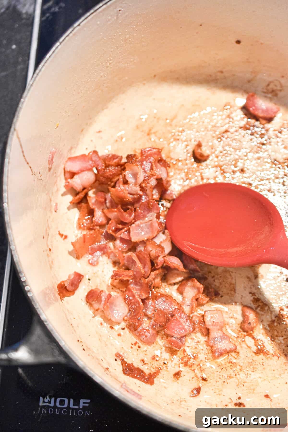 The bacon is added to the Dutch oven.