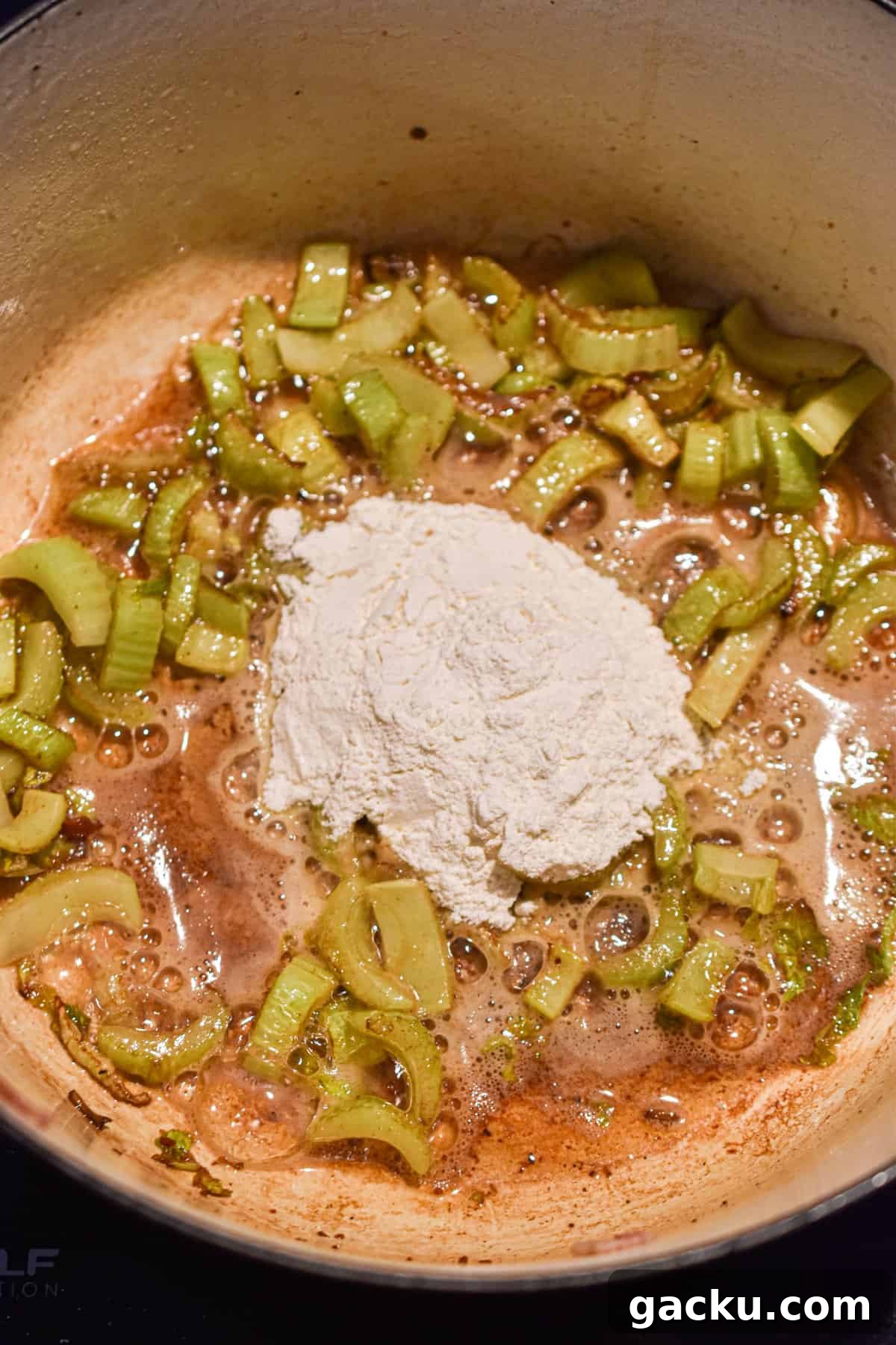 The flour is added to the Dutch oven with the celery and onion.