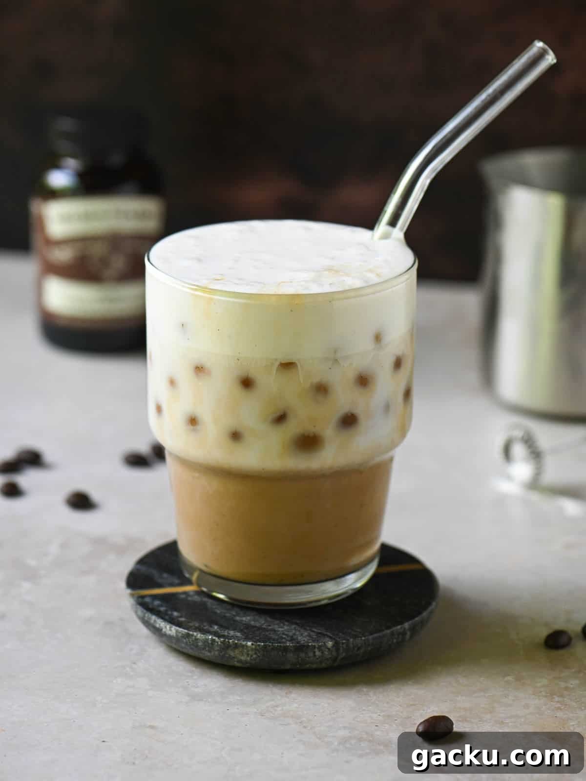 Eye-level view of a vanilla bean latte on a brown surface.