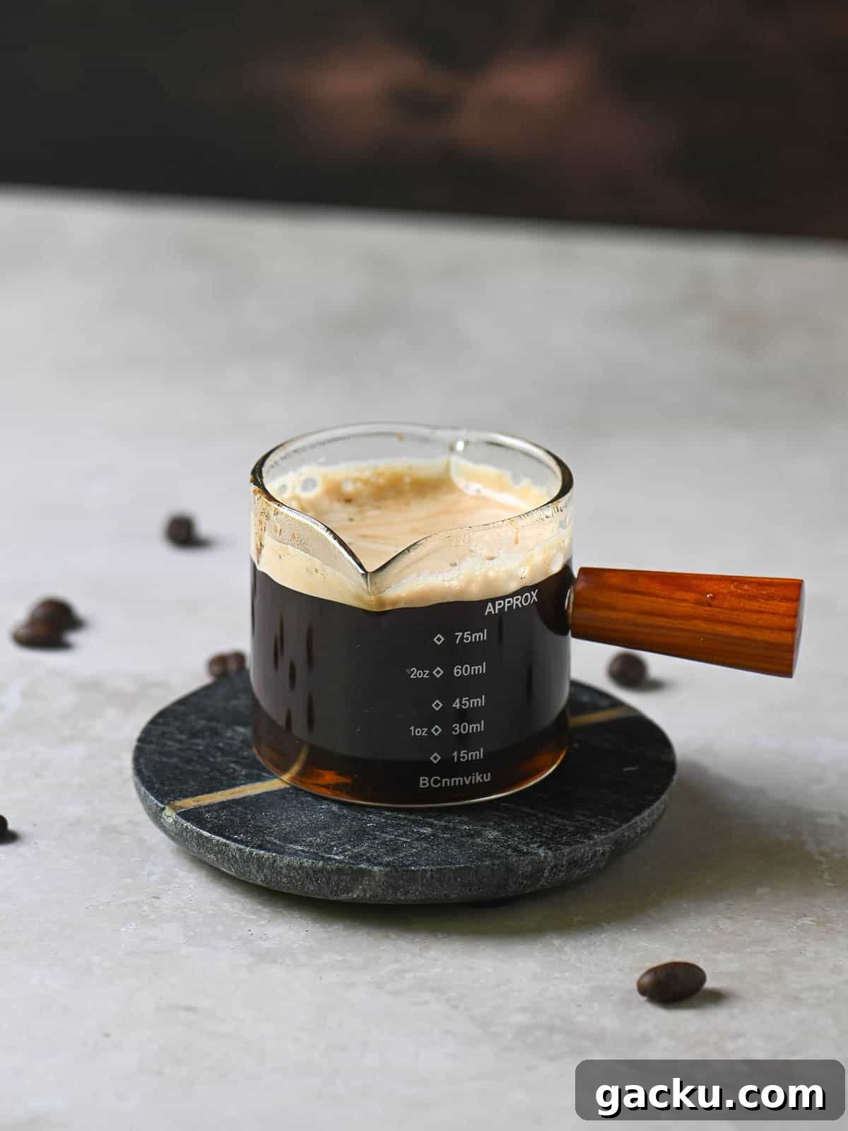 Espresso into a small clear glass holder with a wooden handle.