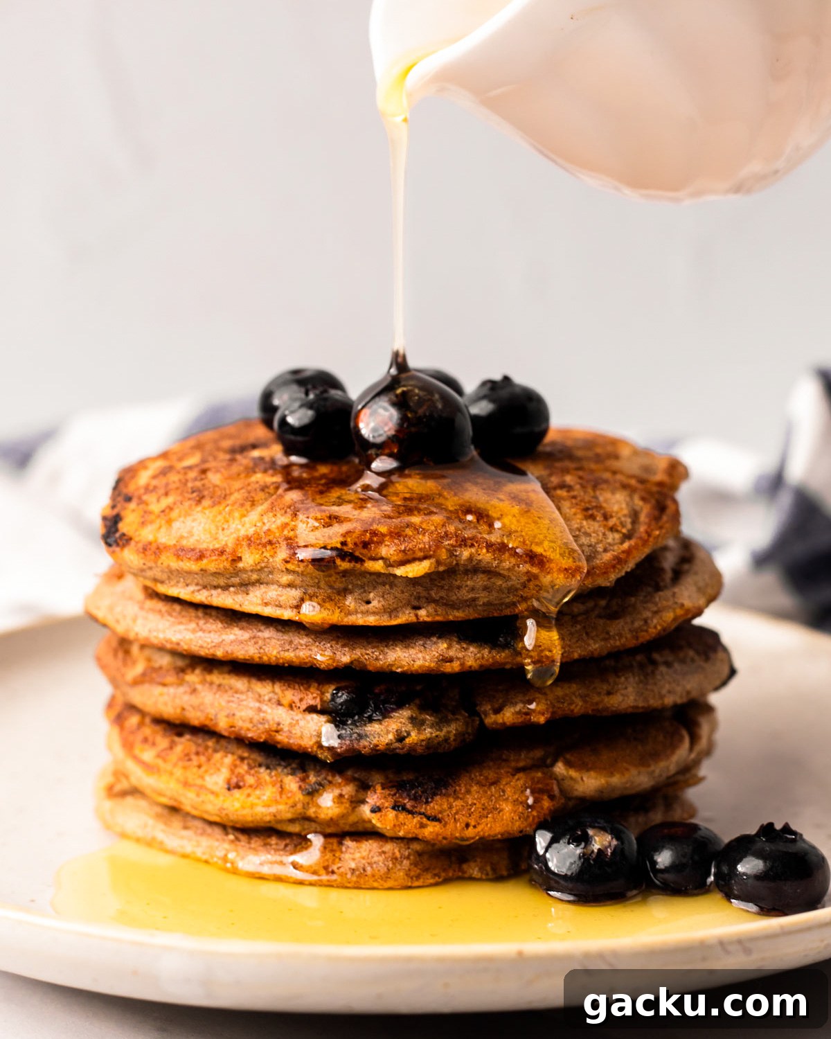 Drizzling a stack of the vegan blueberry pancakes with maple syrup.