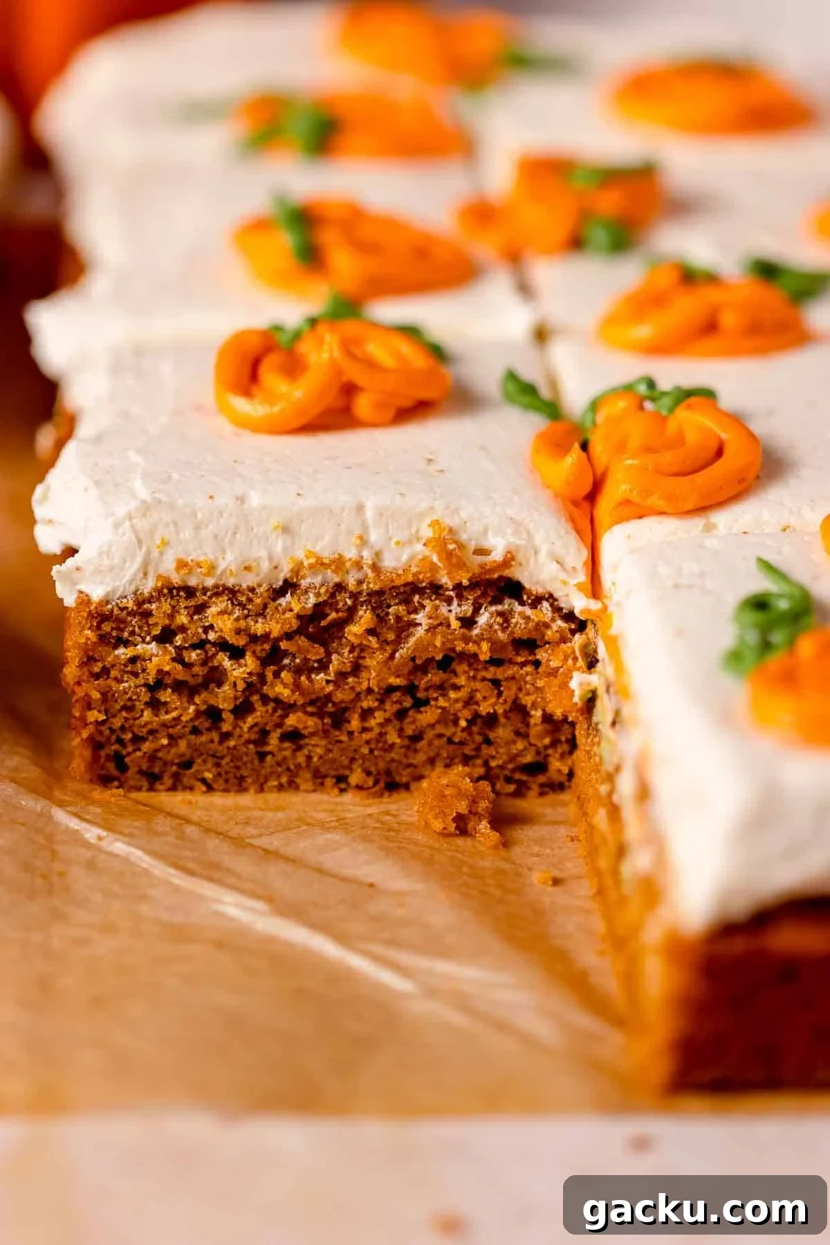 pumpkin cake on parchment paper frosted with white frosting and orange pumpkins