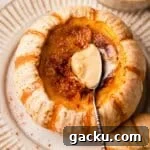 creme brulee with spoon inside of a mini orange and white pumpkin