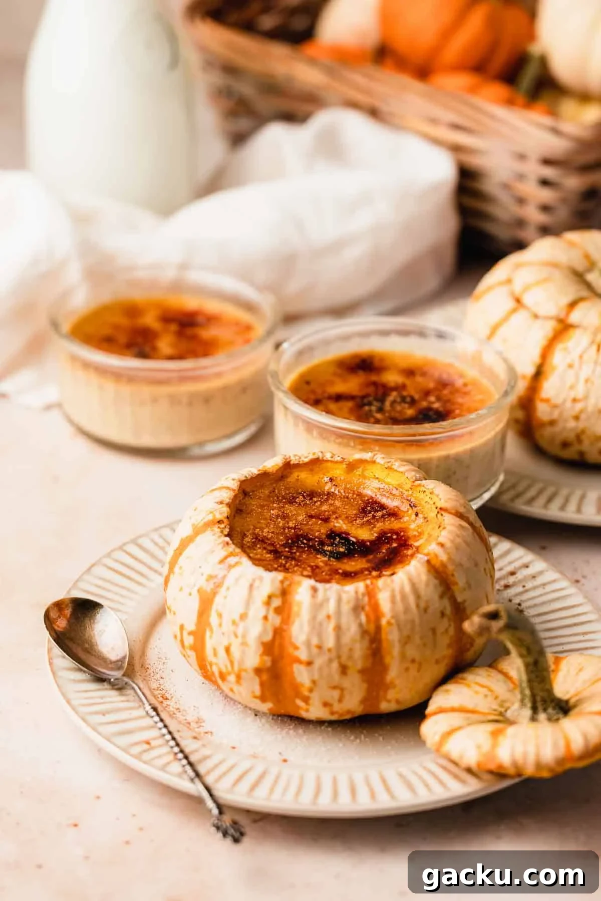 creme brulee inside of pumpkins and ramekins on a table with glass milk pitcher