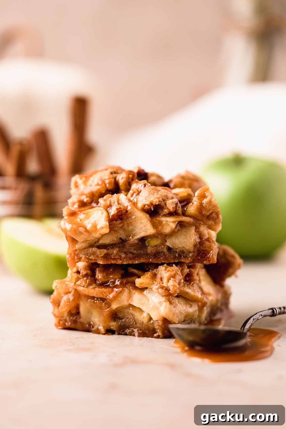 stacked apple pie bars with caramel sauce and spoon