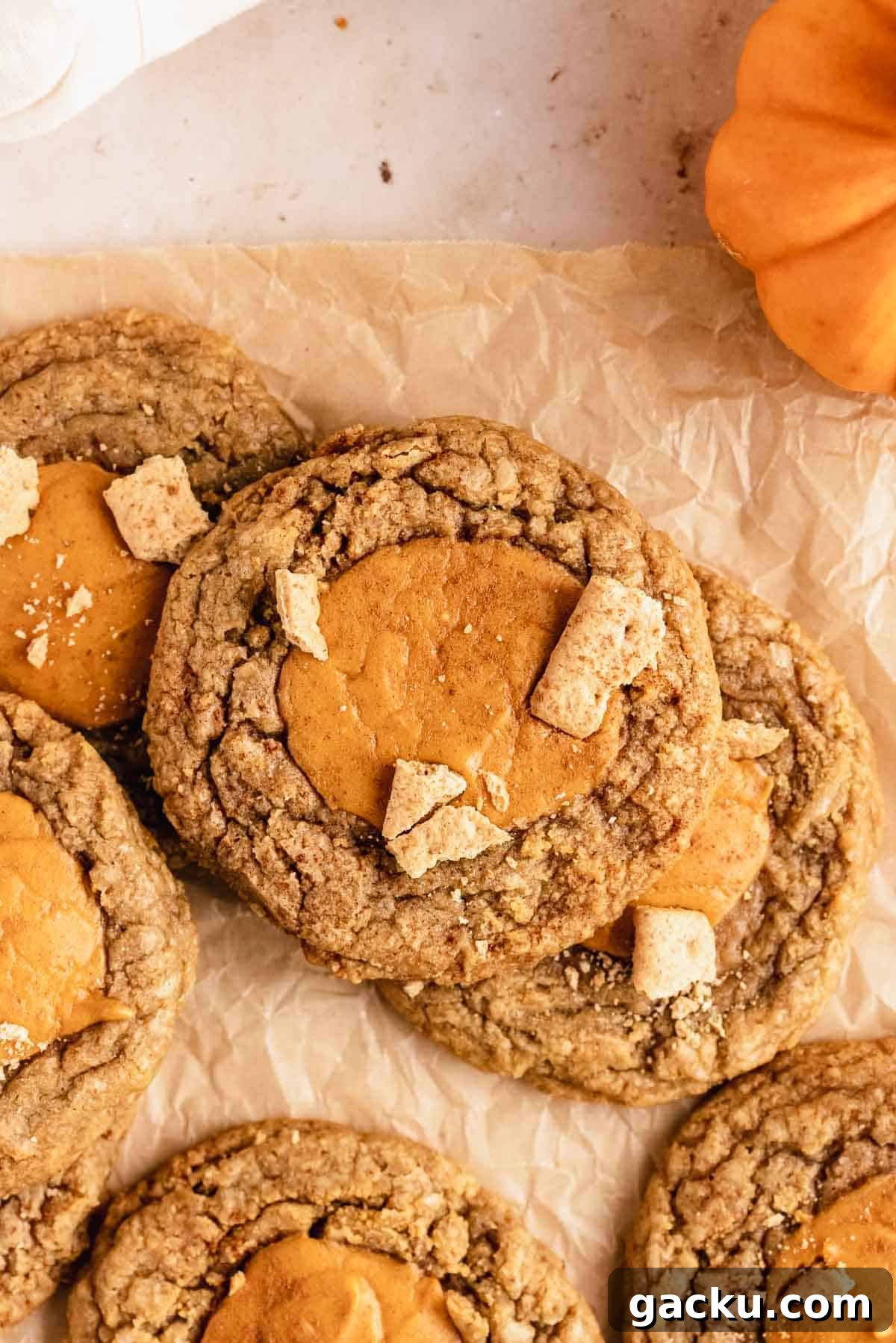 pumpkin cheesecake cookies on parchment paper with pieces of graham crackers