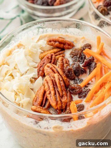 Pecans, raisins, carrots, and coconut on bowl of carrot cake overnight oats.