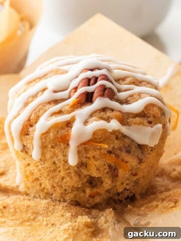 Icing drizzle over baked carrot banana muffin on brown paper.