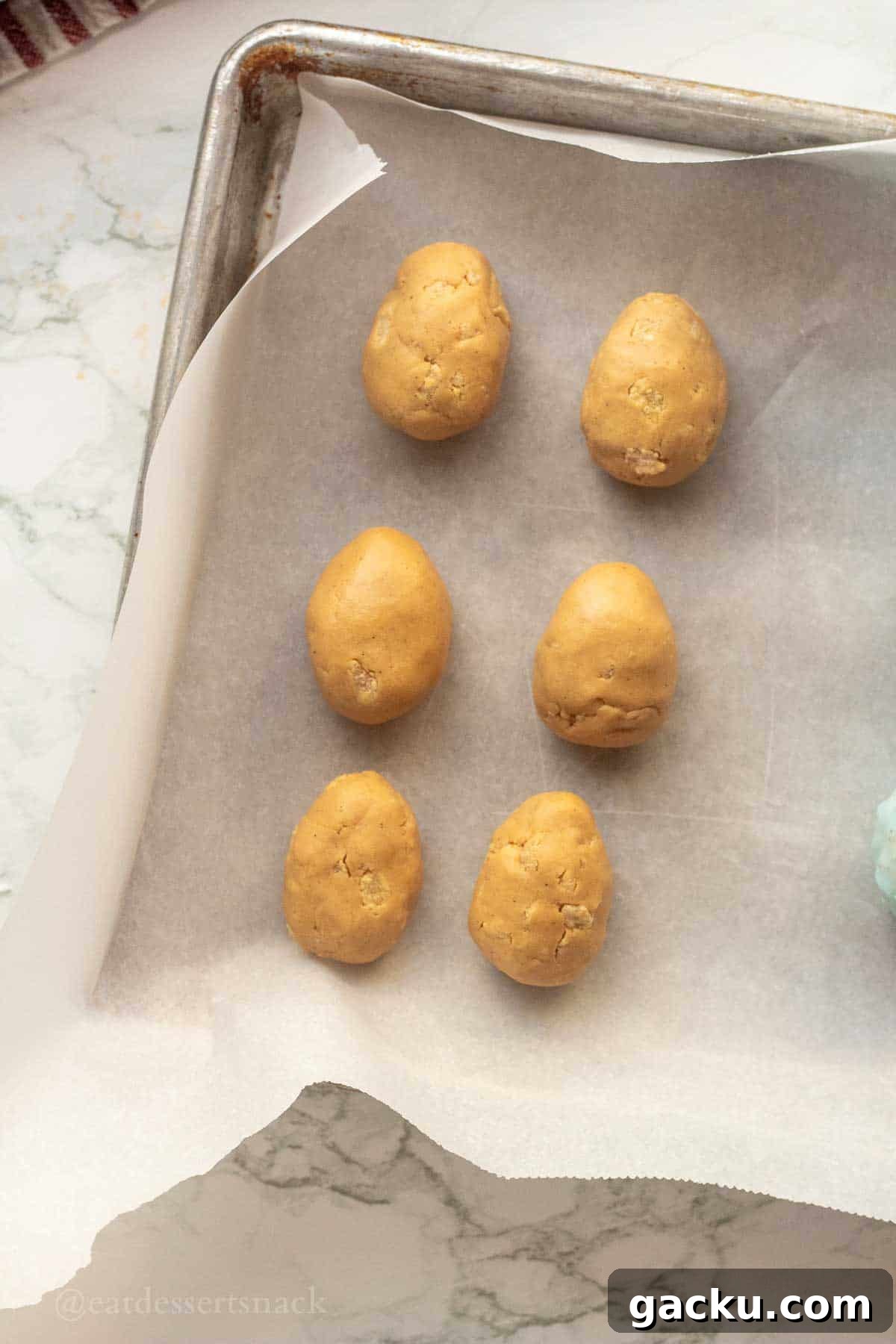 Rolled peanut butter eggs on parchment paper.