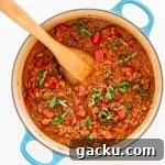 Bolognese sauce in a dutch oven with a wooden spoon.