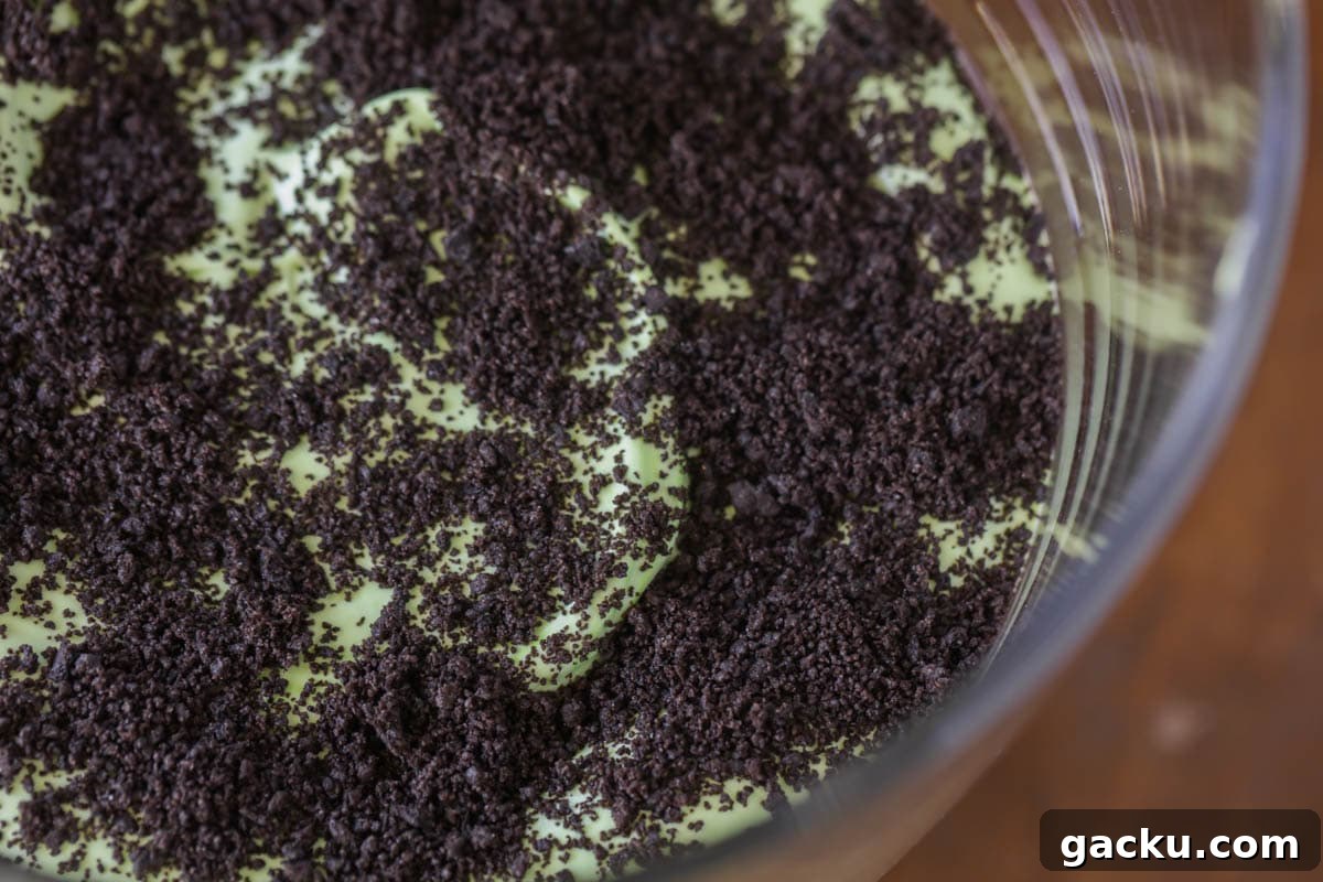 Oogie Boogie Halloween Trifle Recipe: Spooky Layered Dessert Tutorial 5 Oreos sprinkled on green layer for Oogie Boogie Trifle.