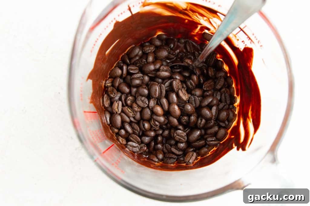 A glass measuring cup with melted chocolate and coffee beans in it.