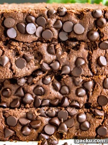 A stack of four pieces of chocolate coffee banana bread with a plant behind them.