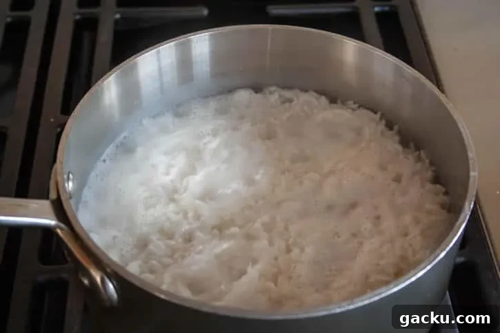 How to Cook Fluffy White Rice Every Time 8 Perfect White Rice simmering in a pot from themerchantbaker.com