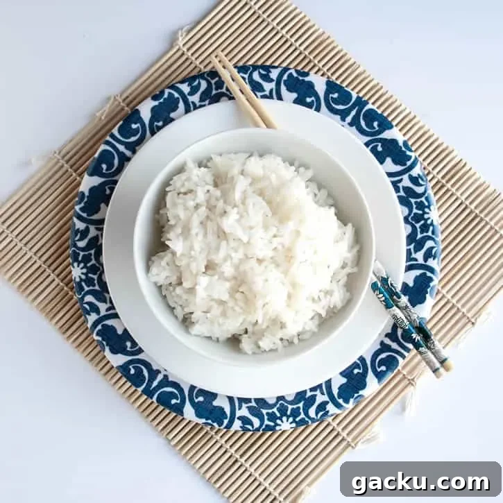 How to Cook Fluffy White Rice Every Time 3 A bowl of Perfect White Rice presented on a plate with chopsticks from themerchantbaker.com